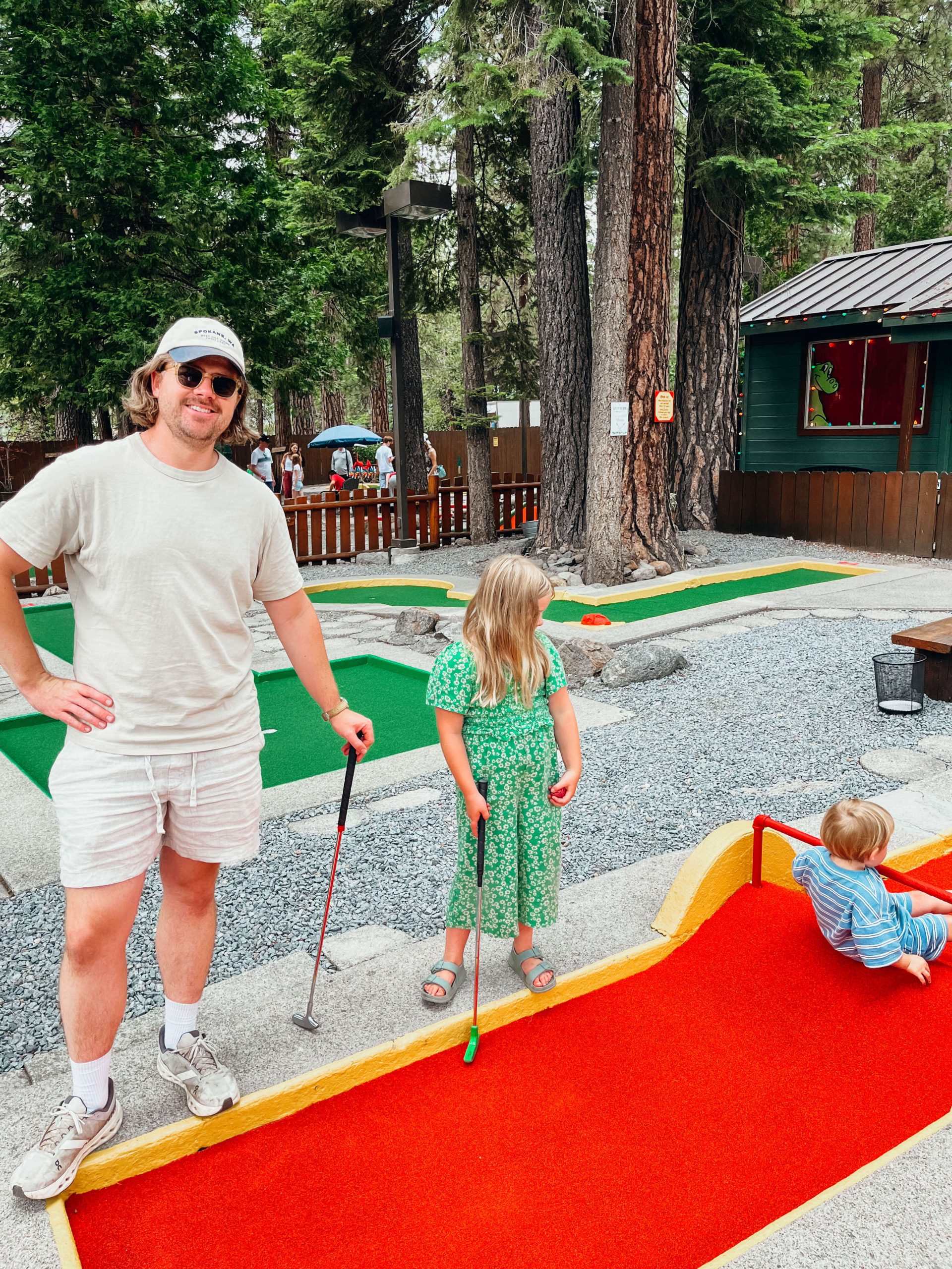 Father and two children pose for photo next to red course hole at Kings Beach Mini Golf Course Lake Tahoe