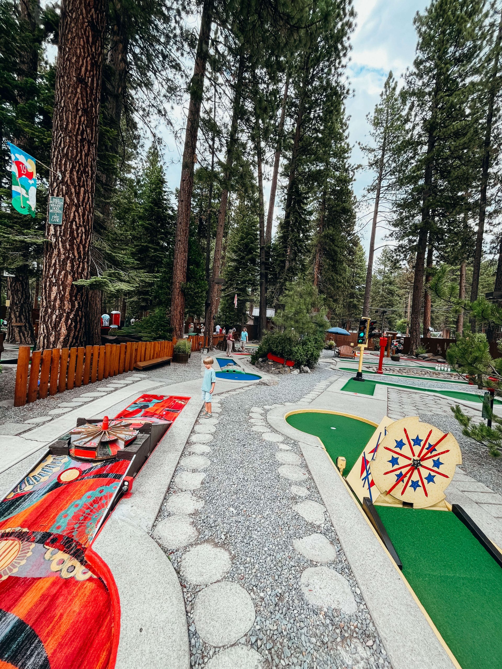 Two holes at King's Beach Mini Golf, one with red colorful carpet and one with green carpet.