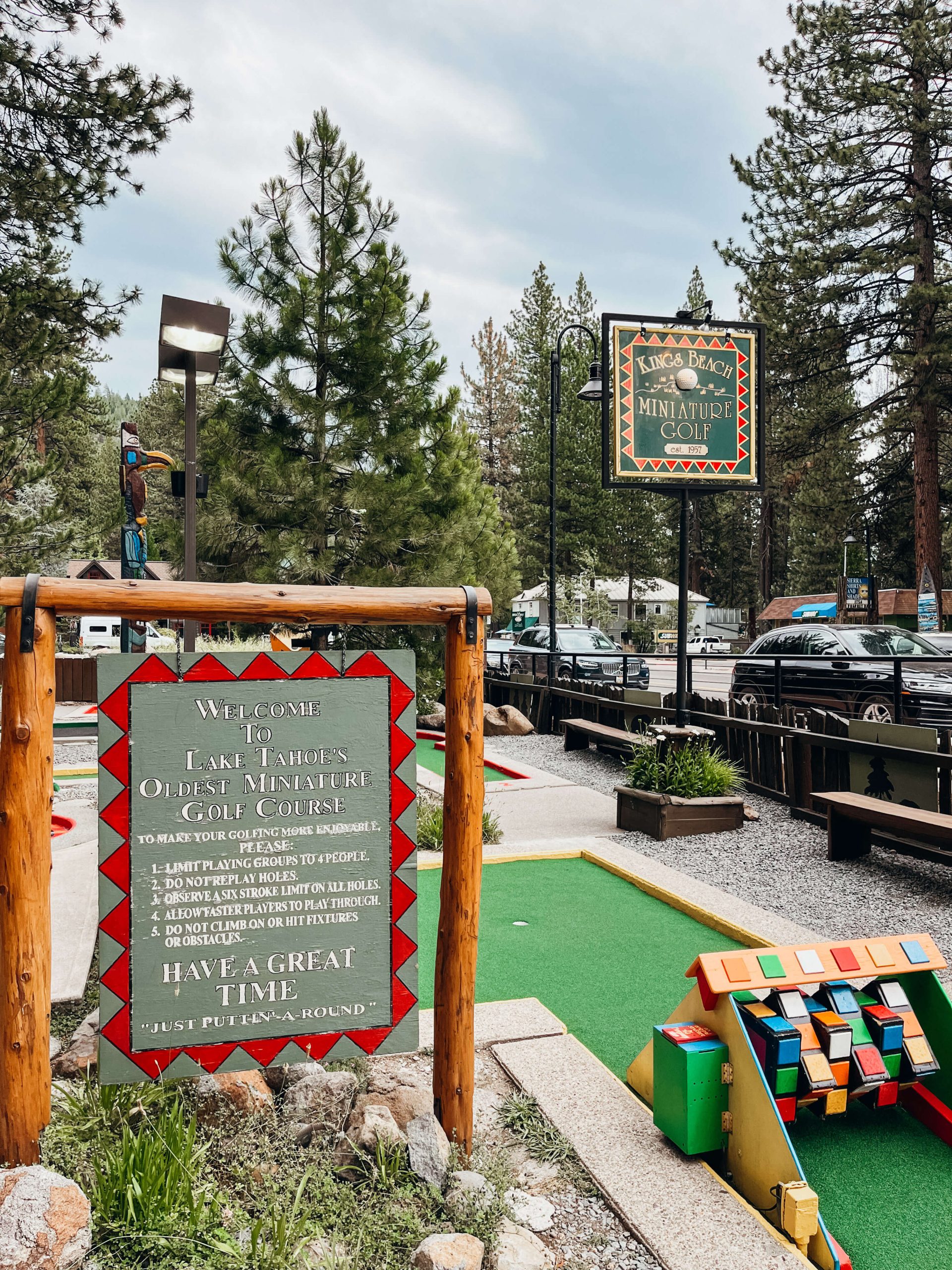 Hand-painted sign saying 'Lake Tahoe's Oldest Mini Golf Course" next to a colorful mini golf trap on green carpet