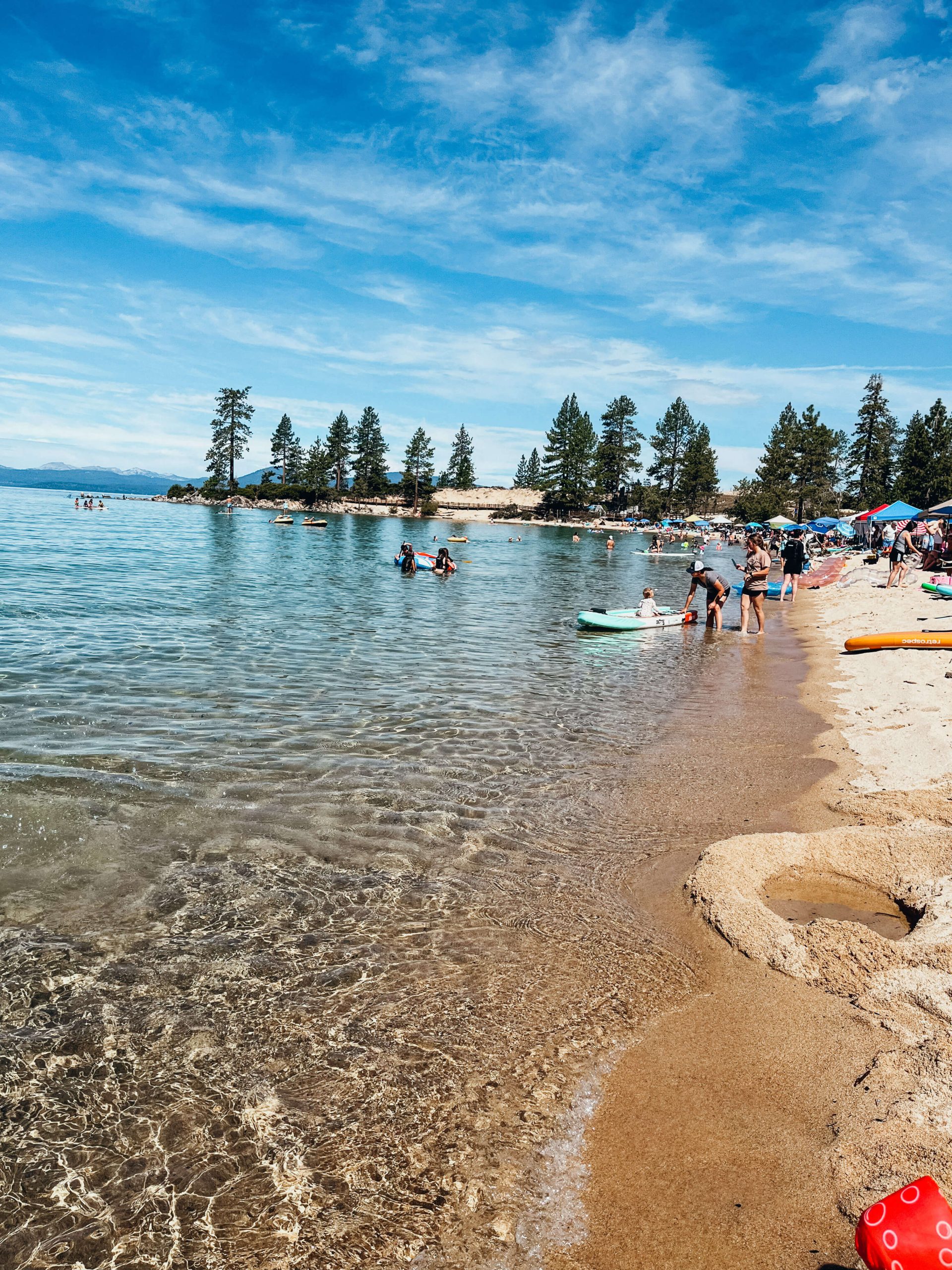 Long sandy beach dotted with umbrellas and pine trees at Sand Harbor State Park
