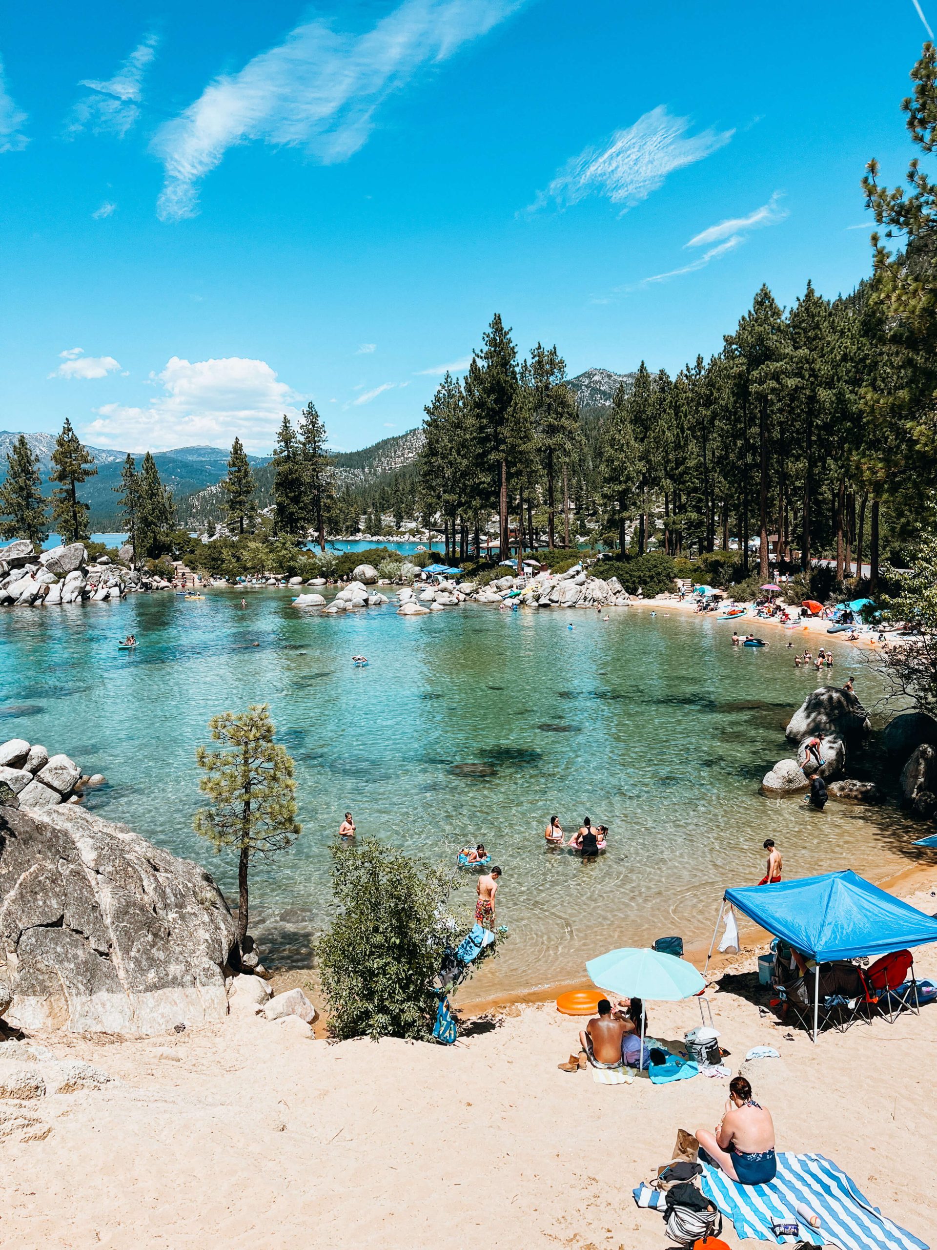 Sandy cove with blue and green water hugged by pine trees and boulders at Sand Harbor State Park
