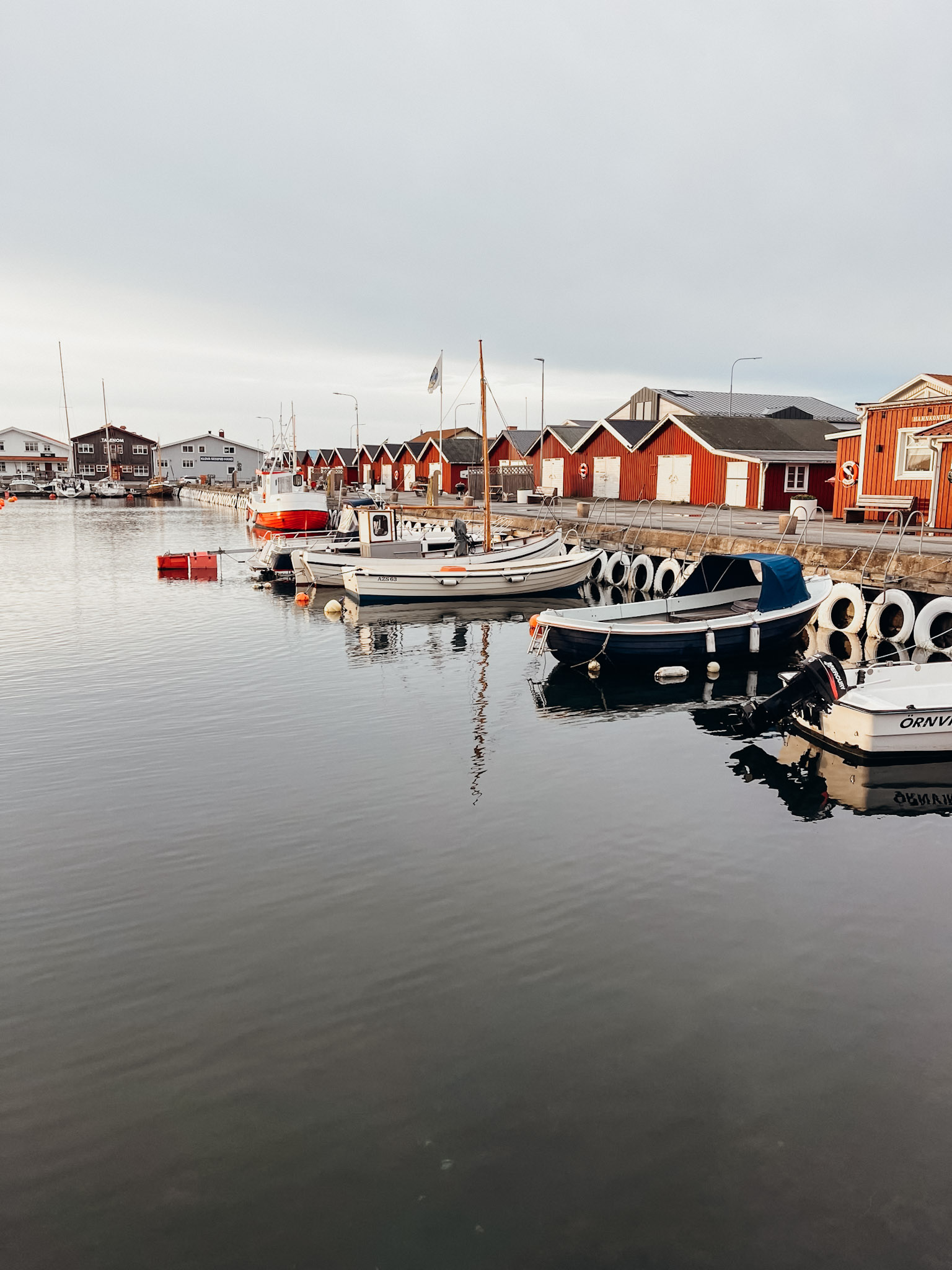 Red and white boat houses line dock with white motor boats at Hönö Klåva Hamn