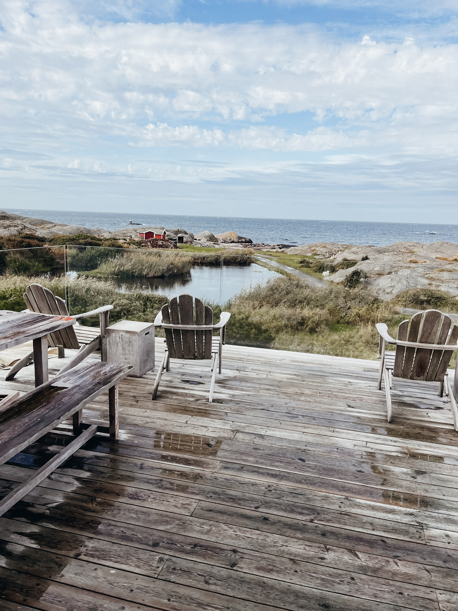 Wooden deck with wooden picnic table and lounging chairs looking out over the sea on Hono Island in Sweden