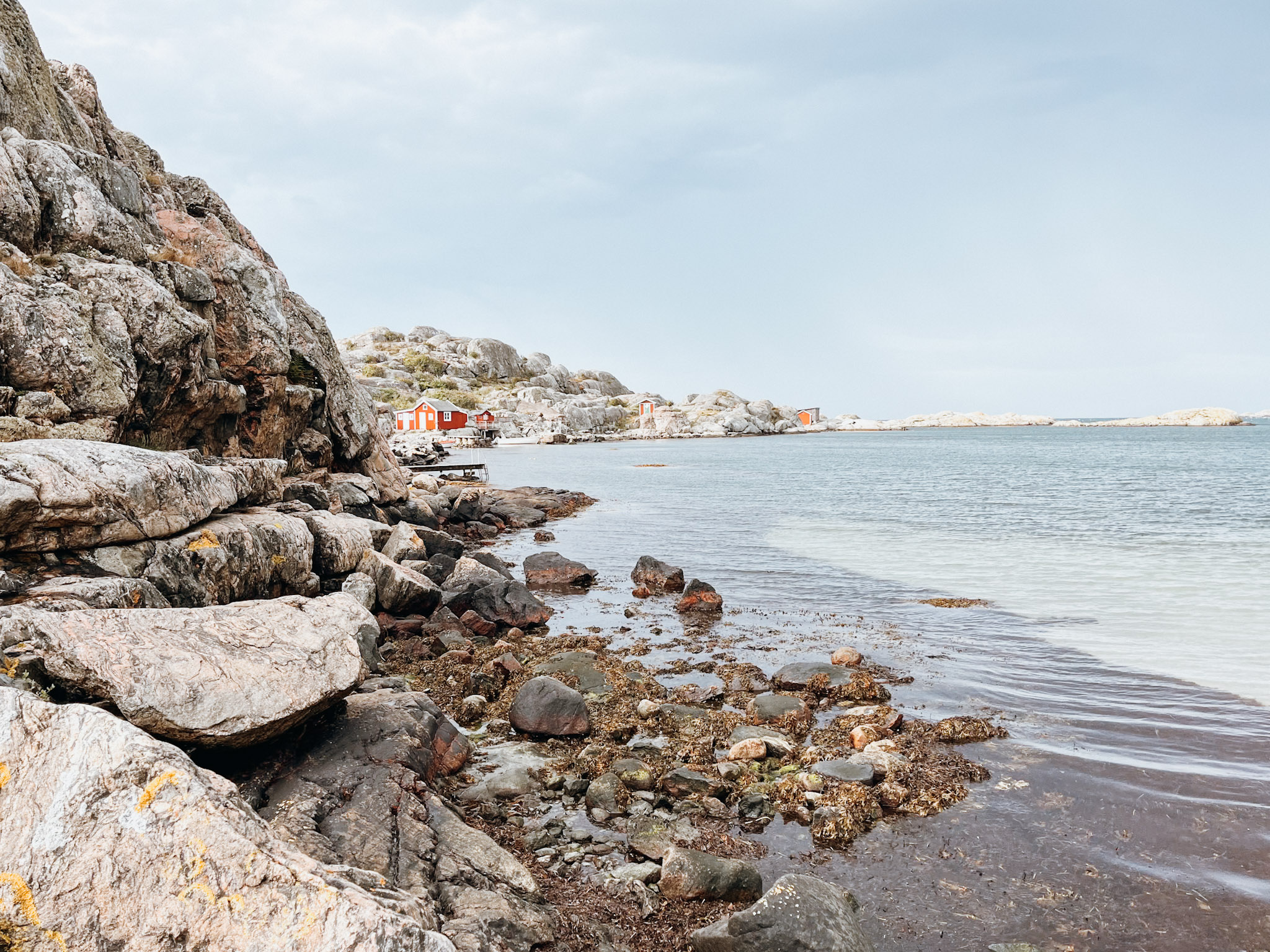 Clear water next to rocky coastline with a red fishing hut on Hönö Island (Bådevi)