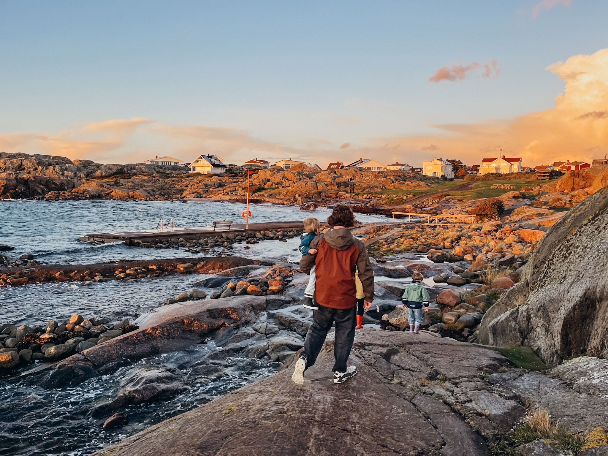 Father and children next to the sea on a rocky coastline as the sunsets on Hönö in Sweden