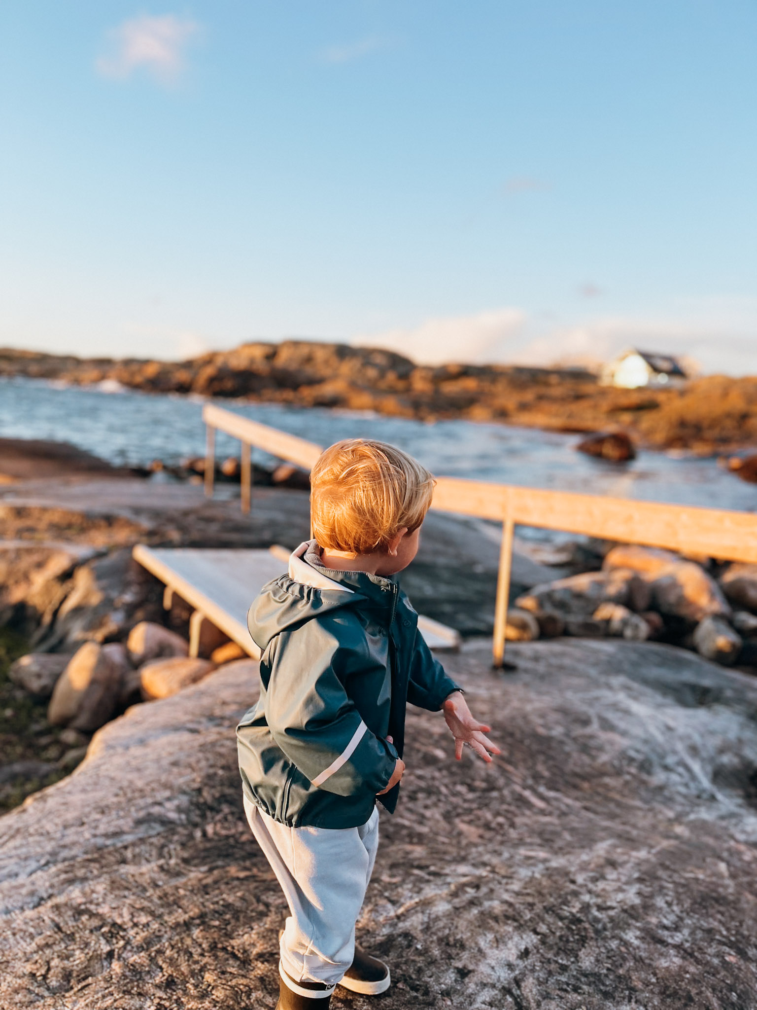 Child looks away from camera as the sun sets on a rocky coastline on Hönö Sweden