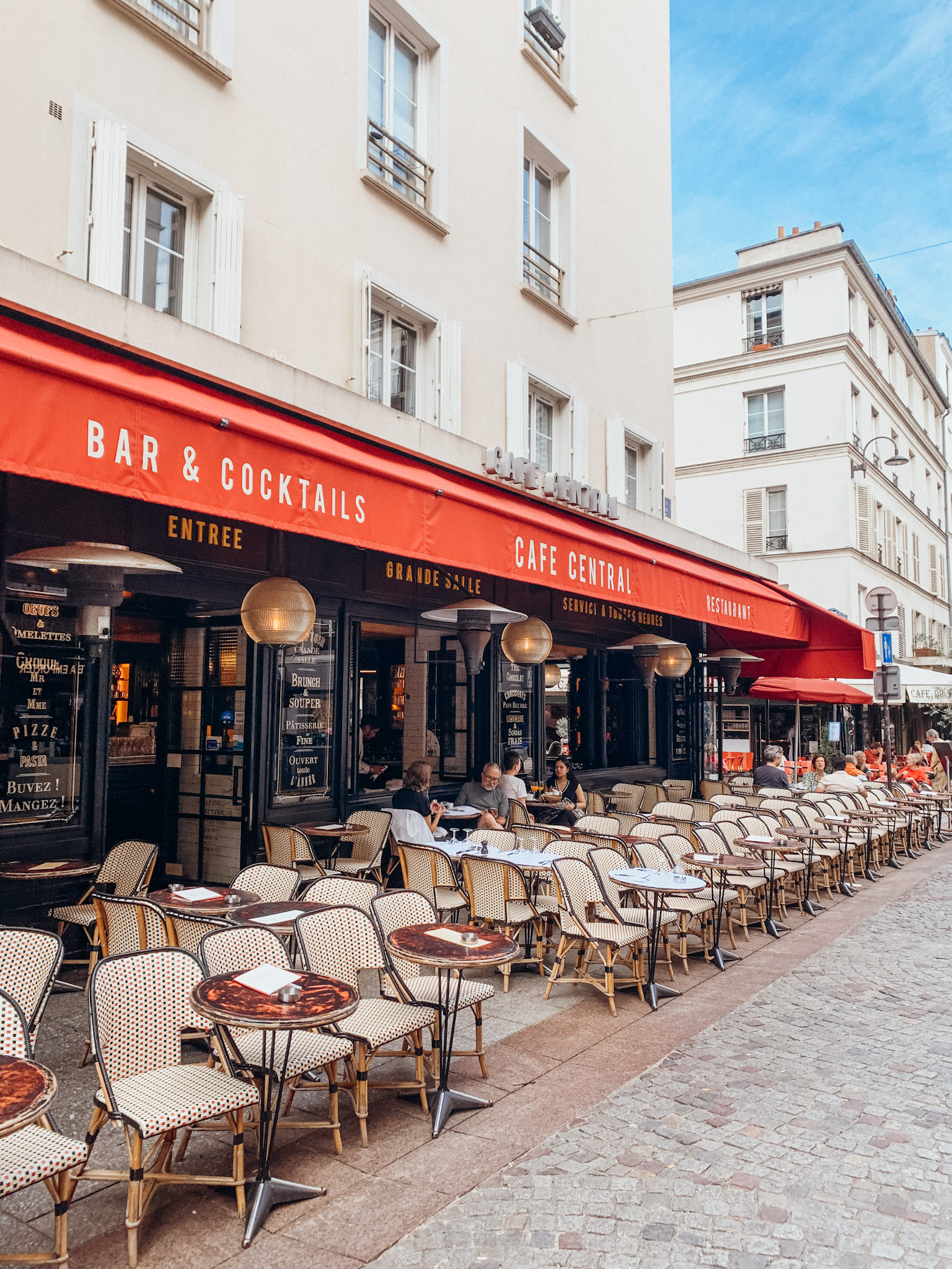 Cafe in Paris with outdoor seating and red awning : Paris in May